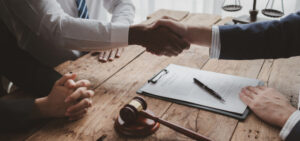 Two people shake hands with a trust on their desk