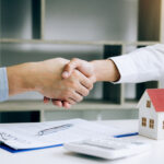 Home sales agents and buyers work on signing new homes and shaking hands.